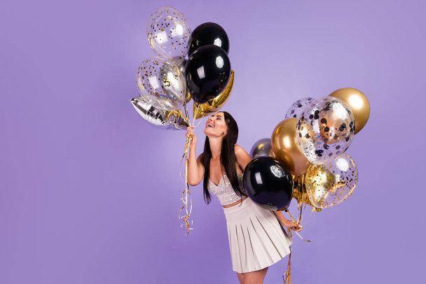 Profile side photo of young charming pretty positive smiling girl hold balloons enjoying weekend isolated on purple color background - Foto, immagini