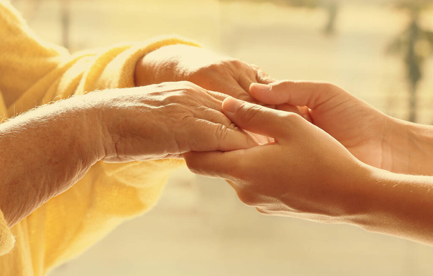 Helping hands on blurred background, closeup. Elderly care concept - Фото, изображение