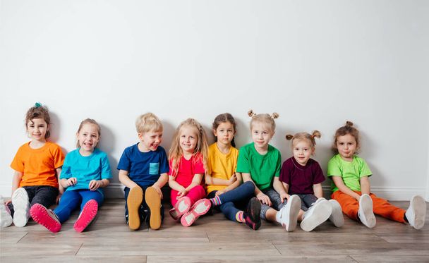 Cheerful children sitting on a floor near the wall - Photo, Image