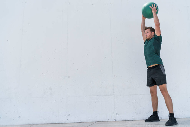 Fit man throwing medicine ball on floor workout - Foto, afbeelding