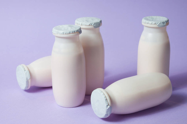 プロバイオティクスとプレバイオティクスの乳製品を含むボトルは、薄い紫色の背景で飲みます。有用微生物とバイオヨーグルト。生物学的に活性な添加物で生産。発酵と食事｜健康食品. - 写真・画像