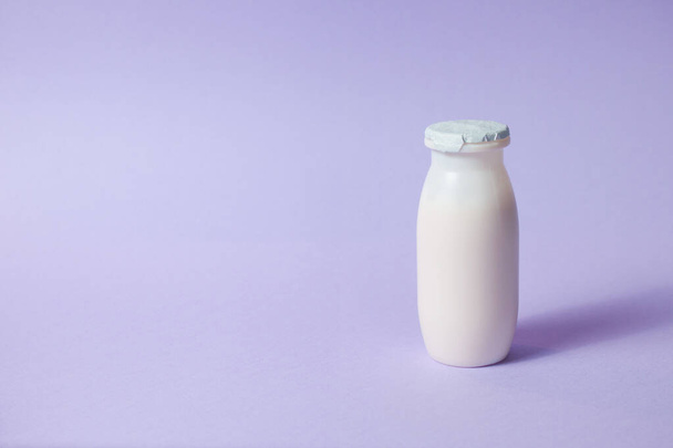 Botellas con probióticos y prebióticos bebida láctea sobre fondo púrpura claro. Yogur bio con microorganismos útiles. Producción con aditivos biológicamente activos. Fermentación y dieta alimentos saludables. - Foto, Imagen