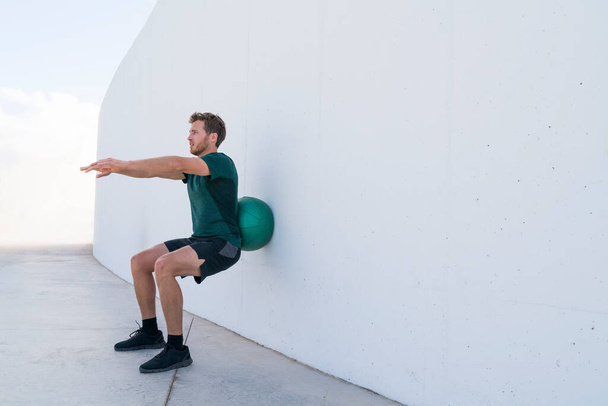 Strength training man doing medicine ball squats - Foto, afbeelding