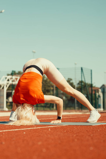 mladá blondýna se učí balancovat ve stojanu a stojanu - Fotografie, Obrázek