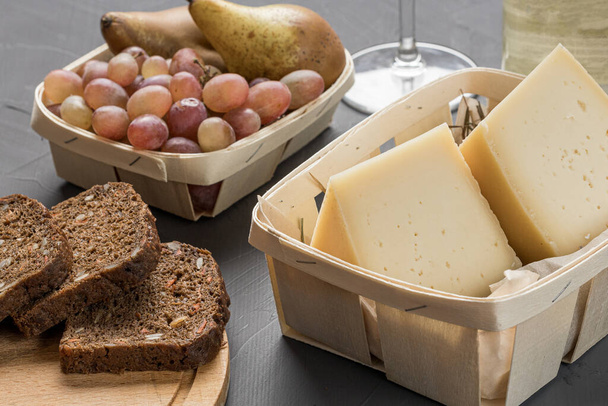 cheese in a wooden basket fruit and bread, still life of handmade food - Photo, Image
