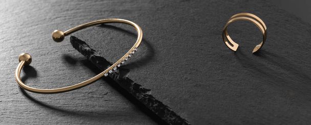 Bracelet moderne doré avec diamants et bague dorée sur plaques de pierre noire - Photo, image