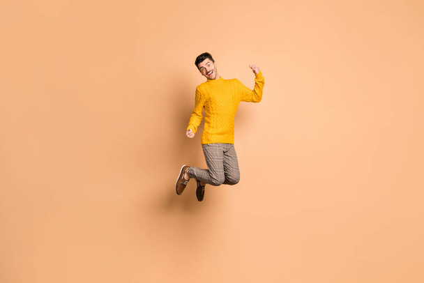 Full length photo portrait of excited man jumping up isolated on pastel beige colored background - Photo, image