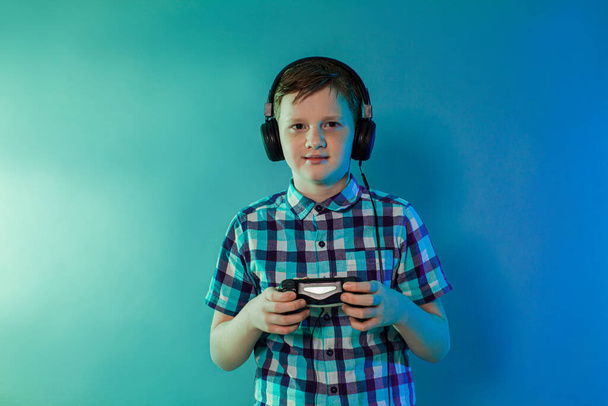 Teenager goy with headphones on his head with a joystick playing - Foto, imagen