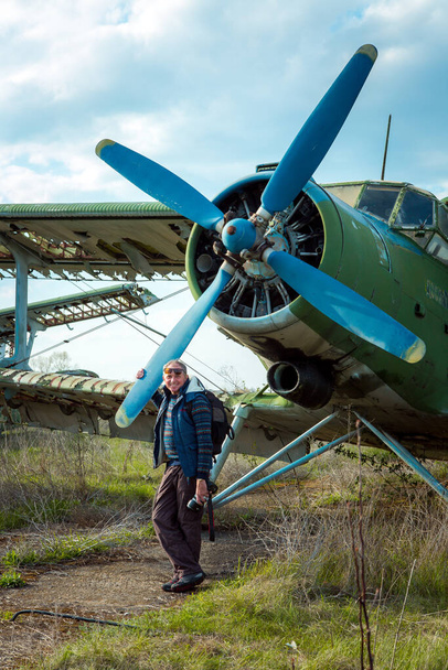 Un homme d'âge moyen près d'un vieil avion soviétique abandonné. Avion sur le terrain de l'ancien aéroport. - Photo, image