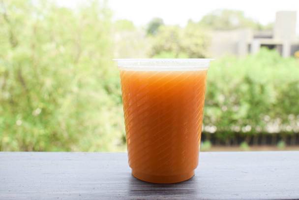 Świeżo wyciskany, słodki sok pomarańczowy, domowej roboty napój serwowany na stole w ogródku. Zdrowy naturalny napój organiczny. Otwarte środowisko zielone na zewnątrz - Zdjęcie, obraz