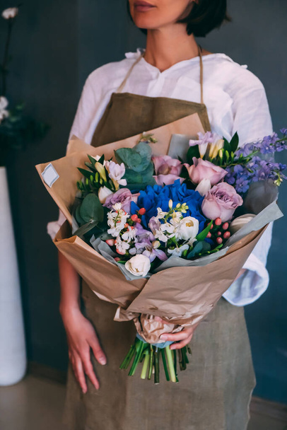 Woman florist holds a beautiful colorful blooming summer bouquet - Foto, afbeelding