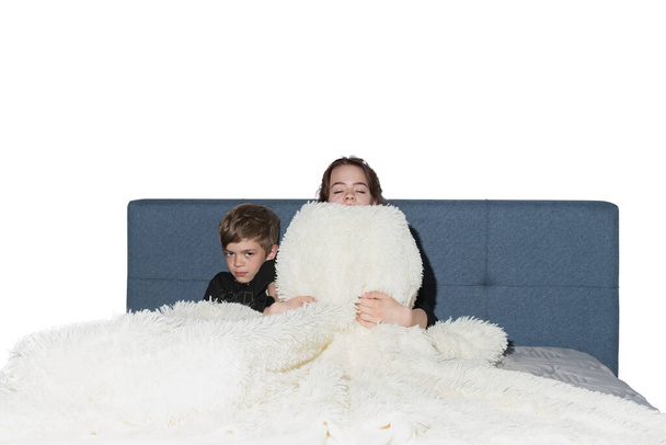 Brother and sister play on the bed with a new white terry cape - Valokuva, kuva