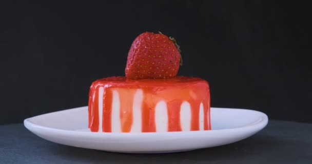 Fruitcake versierd met verse aardbeien. Toetje op schotel op zwarte achtergrond. Draaiende video. - Video