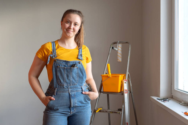 Professional repairwoman posing with tool on ladder doing a home renovation. DIY repair - Zdjęcie, obraz