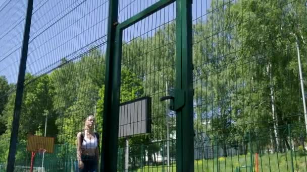 young fit athletic blond pretty girl in sportswear opens door at sports ground - Footage, Video