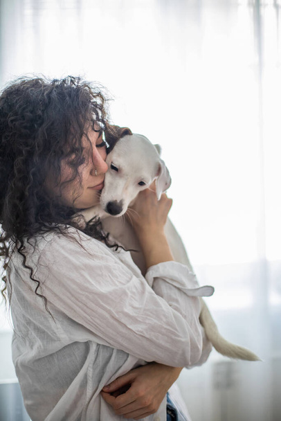 Happy curly brunette woman pet owner holding dog Jack Russell Terrier breed feeling love friendship - Fotó, kép