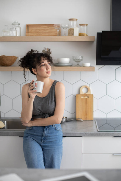 Pleasant domestic woman relaxing at modern kitchen chatting use smartphone white cuisine interior - Φωτογραφία, εικόνα