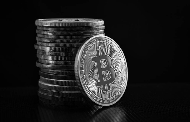One silver bitcoin and stack of bitcoins over black background - Foto, Imagem