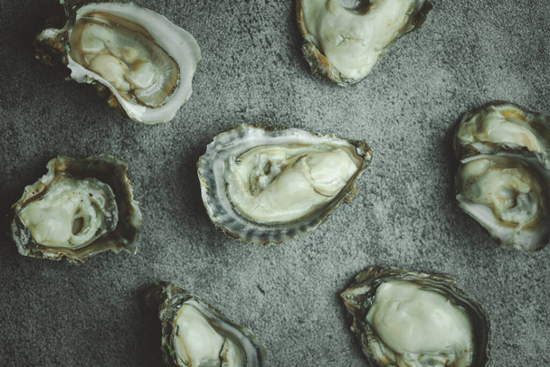 Fresh raw oysters on a black stone background. Top view - Foto, Imagen