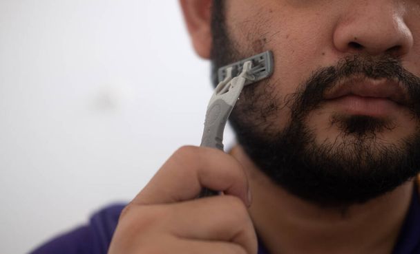 Porträt eines Mannes mit Rasiermesser in der Hand beim Rasieren. Pflegekonzept für Männer. - Foto, Bild