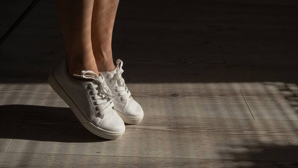 Close-up of female legs in white leather sneakers. - Foto, Imagem