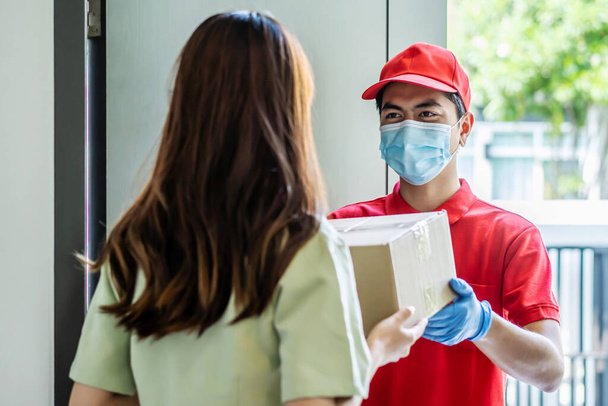 Delivery man in red uniform holdinging parcel boxes to a woman customer - courier service concept - Fotoğraf, Görsel