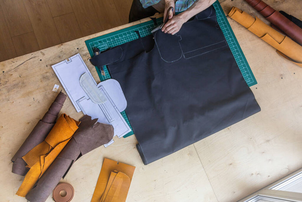Forro del esquema de dibujo del artesano para el bolso en el tejido que crea cuero en taller de cuero del estudio - Foto, imagen