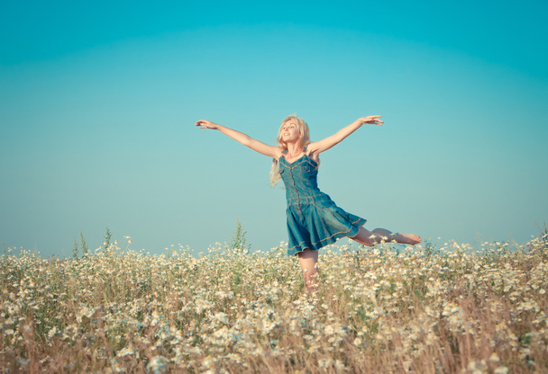The happy young woman jumps in the field of camomiles,with a retro effect - Φωτογραφία, εικόνα