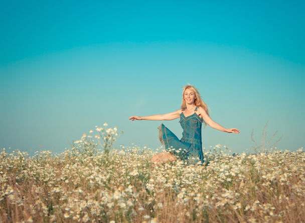 La joven feliz salta en el campo de las manzanillas, con un efecto retro
 - Foto, Imagen