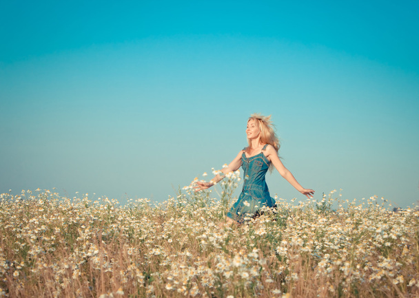 La joven feliz salta en el campo de las manzanillas, con un efecto retro
 - Foto, Imagen