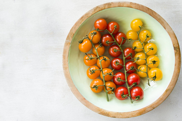 A top view of yellow, red, and orange cherry tomatoes in a - Foto, afbeelding