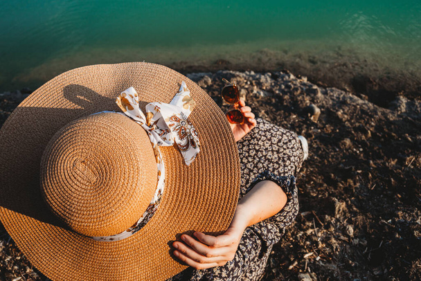 A woman relaxing on the river rocks with a hat in summer - Foto, immagini