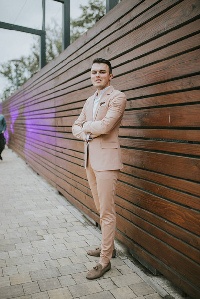 A vertical shot of a young handsome Caucasian male wearing a nice elegant suit - Fotó, kép