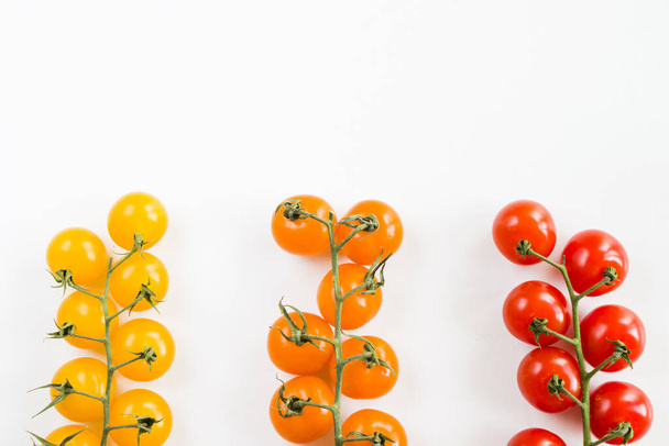 Uma vista superior de tomates cereja maduros de cores diferentes em hastes isoladas no fundo branco - Foto, Imagem