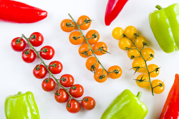 A op view of colorful bell peppers and cherry tomatoes on a white background - Fotó, kép