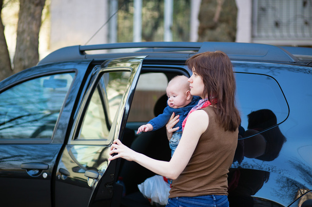 Young mother with her baby getting into a car - Foto, Bild