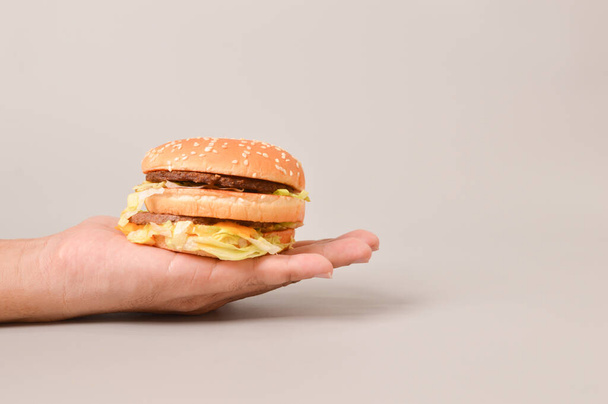 Hand holding burger isolated on grey background - Zdjęcie, obraz