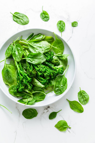 Organic spinach with broccolini (bimi) in bowl on white background. - Photo, Image