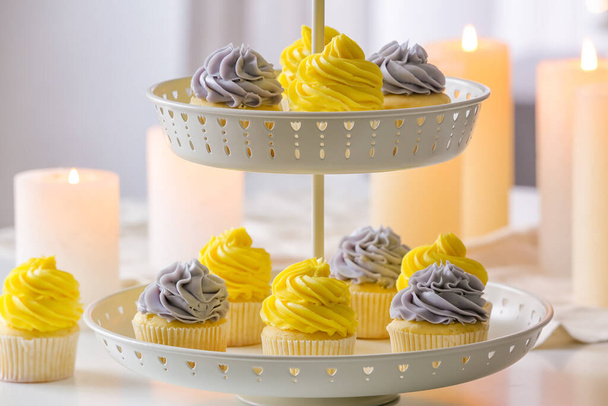 Dessertstand mit leckeren Cupcakes und brennenden Kerzen auf dem Tisch - Foto, Bild