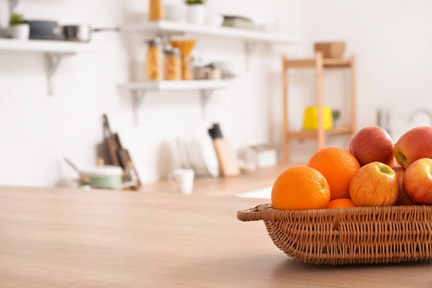 Basket with fresh fruits on wooden table in kitchen - Φωτογραφία, εικόνα