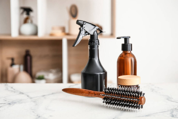 Hair brush and cosmetics on table in room - Fotoğraf, Görsel
