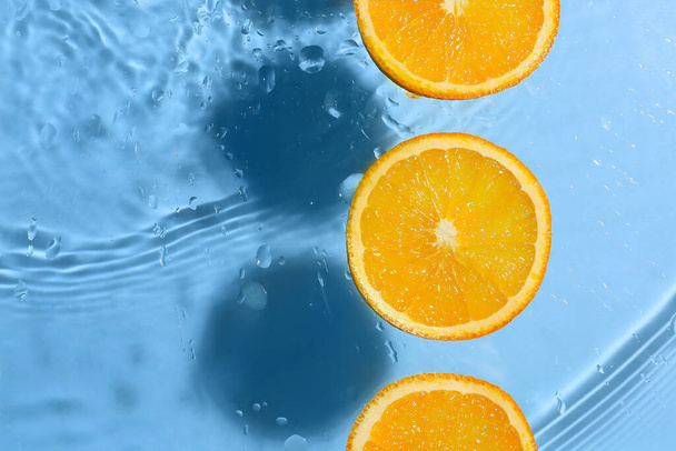 Slices of ripe orange on color background with water drops - Photo, Image
