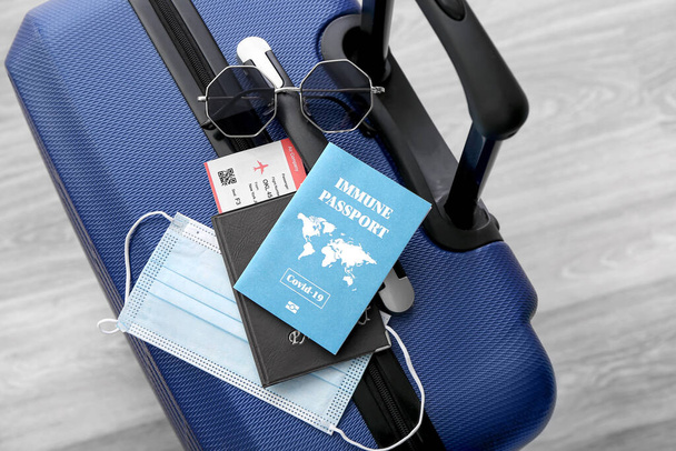 Bavulda dokunulmaz pasaport, güneş gözlüğü, bilet ve tıbbi maske var. - Fotoğraf, Görsel