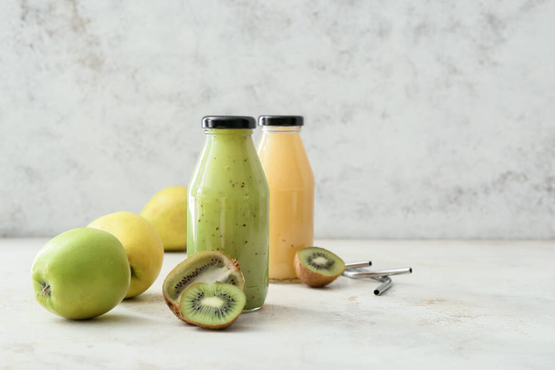 Bottles of healthy smoothie with apples and kiwi on light background - Photo, Image