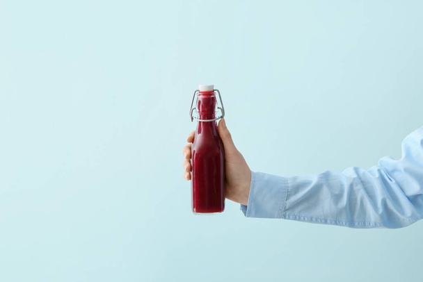 Female hand with bottle of healthy beetroot smoothie on color background - Φωτογραφία, εικόνα