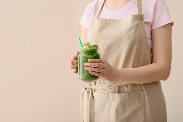 Mujer con tarro de albañil de batido verde saludable sobre fondo de color - Foto, imagen
