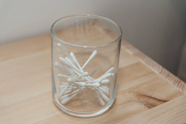 Cotonetes para manter as orelhas limpas em um frasco claro em uma mesa de madeira - Foto, Imagem