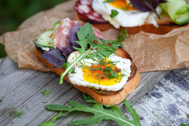 Bruschetta with fried eggs, sausage and herbs. - Foto, imagen
