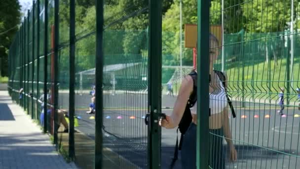 fiatal fitt sportos szőke csinos lány sportruházat nyit ajtót a sportpályán - Felvétel, videó
