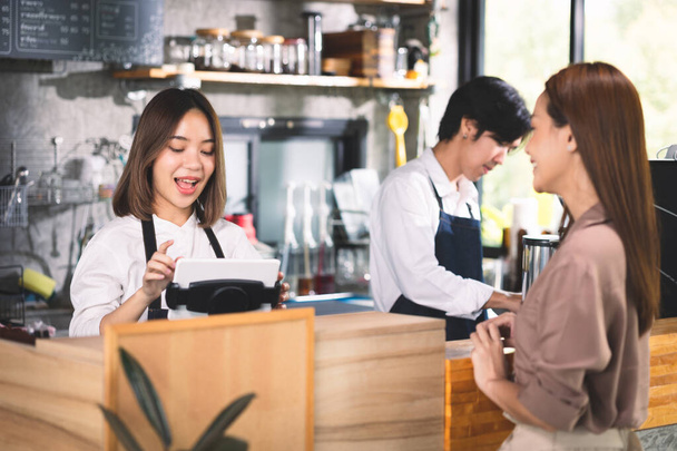 Bir müşteri baristaya sıcak latte sipariş ediyor. Asyalı Personel Kafe 'si sıcak kahve yapıp müşteriye servis yapıyor. Küçük işletme konsepti. - Fotoğraf, Görsel